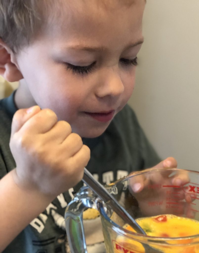 Boy having fun stirring ingredients for Omelette recipe for kids