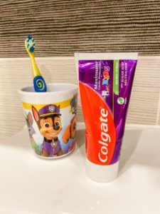 Colgate maximum kids toothpaste on bathroom sink with kids toothbrush in paw patrol toothpaste holder