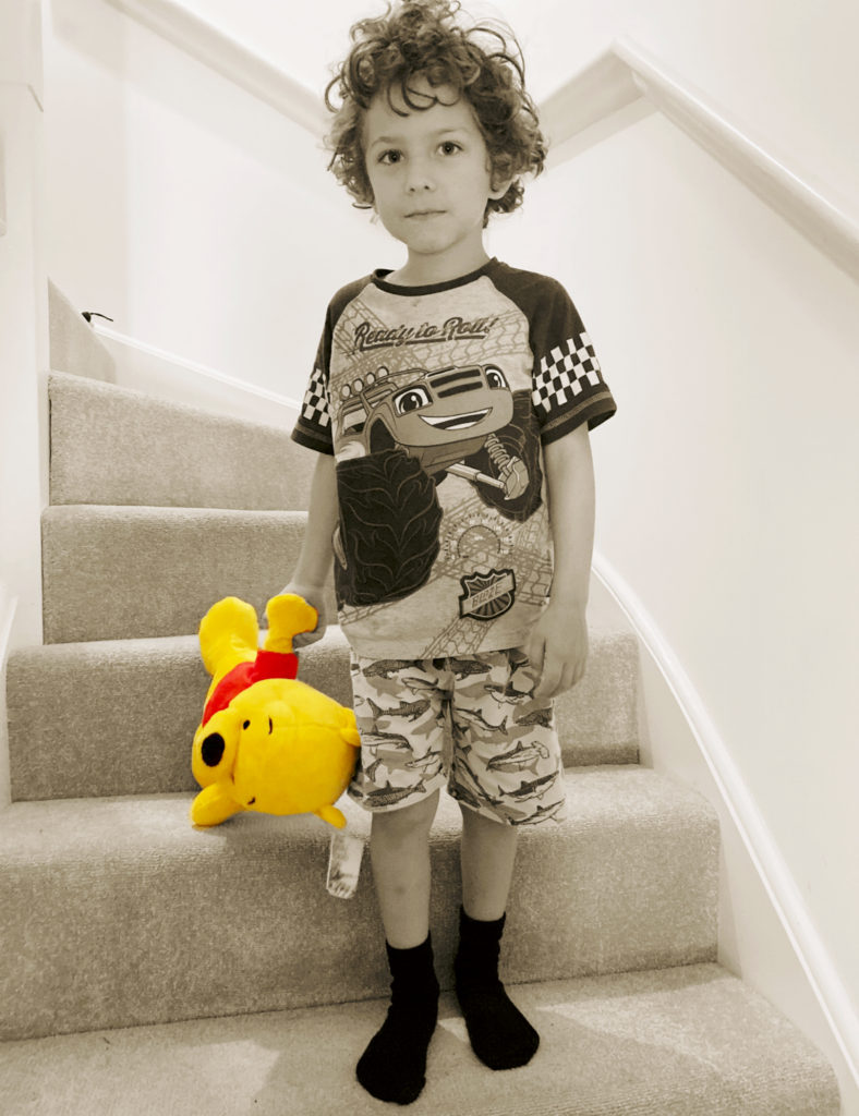 a boy with winnie the pooh as he goes bump bump bump banging his head down the stairs. Black and white photo with winnie the pooh in colour.