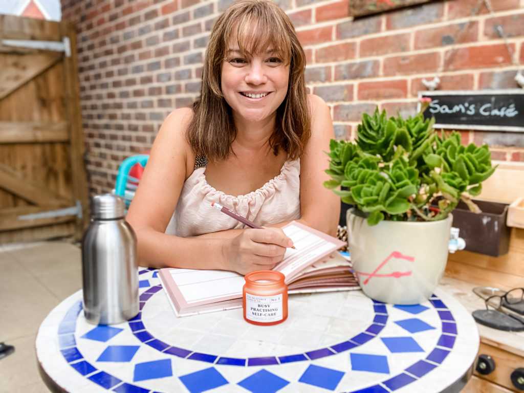Mum sitting on the patio with a notebook and pen working self-development