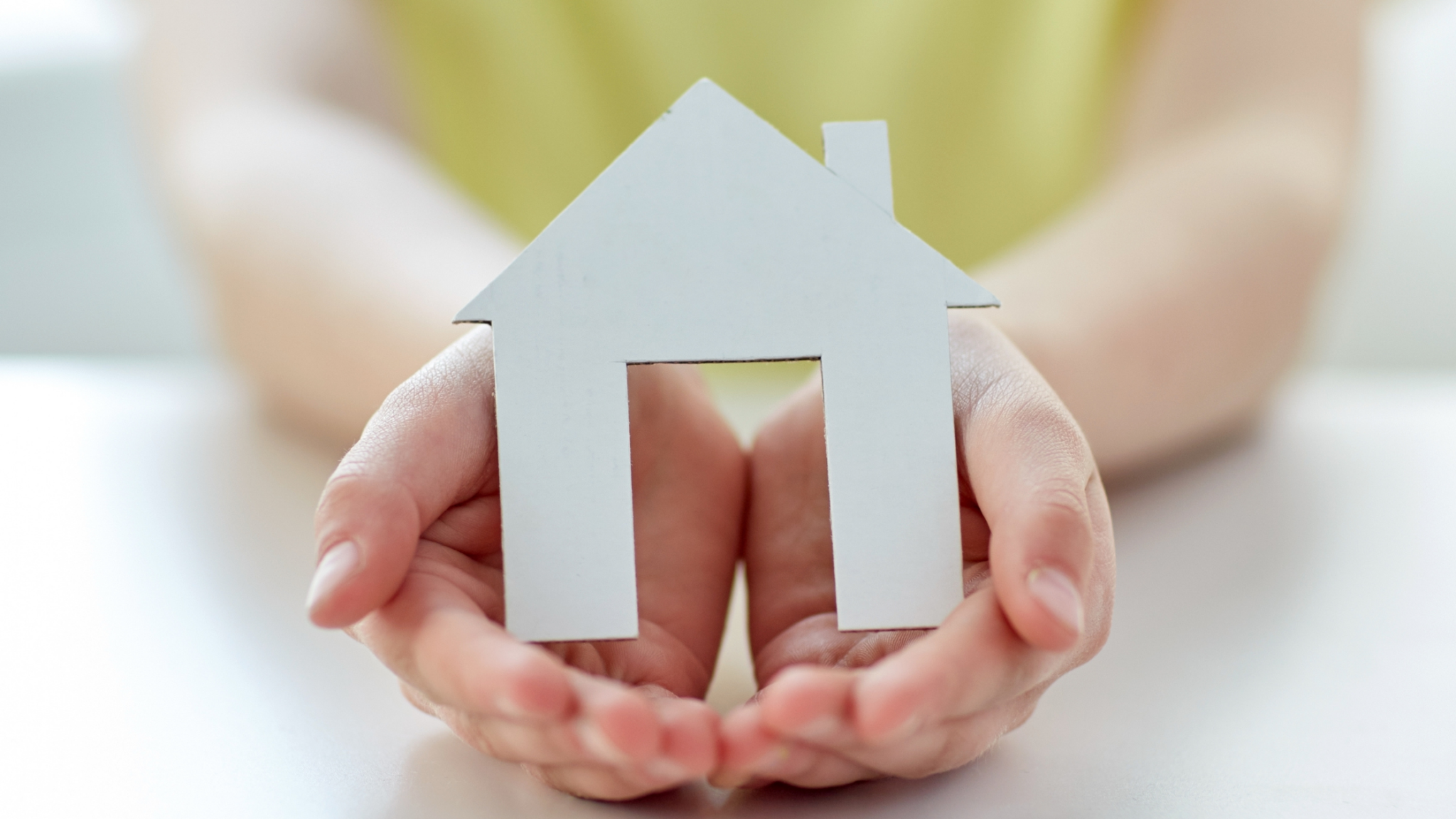 Hand holding a paper house to represent house share