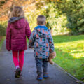 Siblings holding hands walking in a park