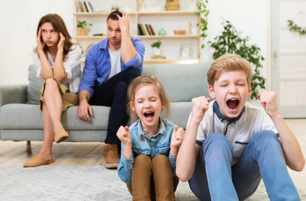 Noisy siblings on the floor yelling and exhausted parents