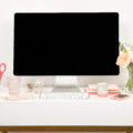 A small desk organised really nicely with flowers and coral stationery