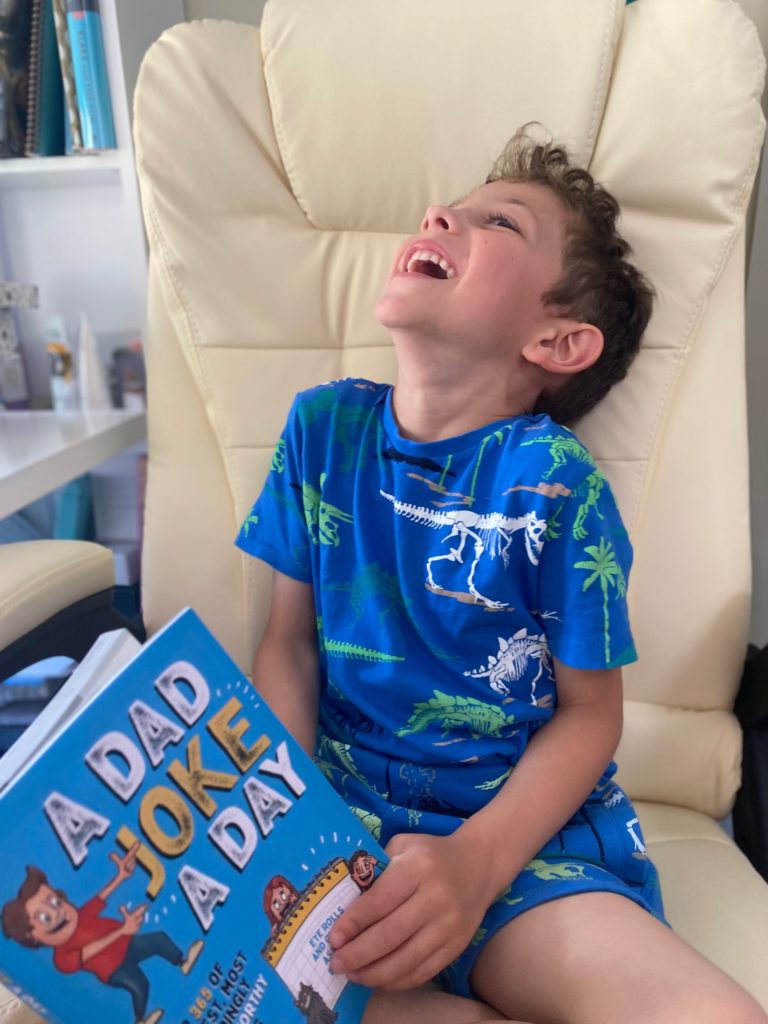 Boy lauging at the book a dad joke a day