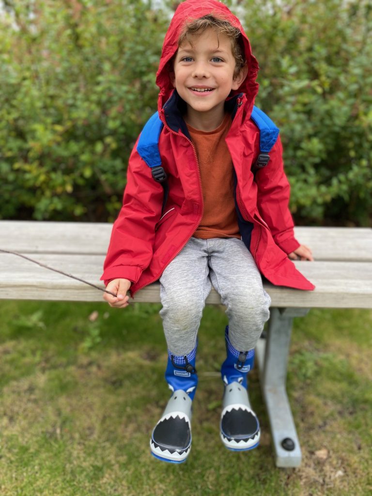 Happy boy wearing regatta coat and wellies at the park