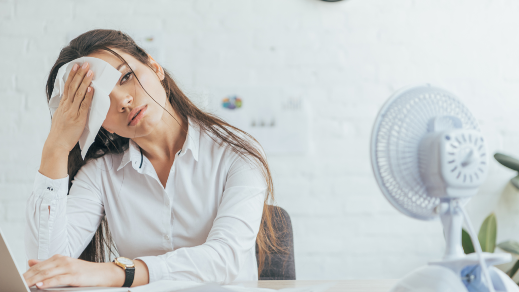 working mum at her desk experiencing excessive heat which is making her sweat