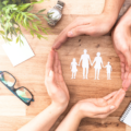 Hands together around a paper cut out family to represent foster care