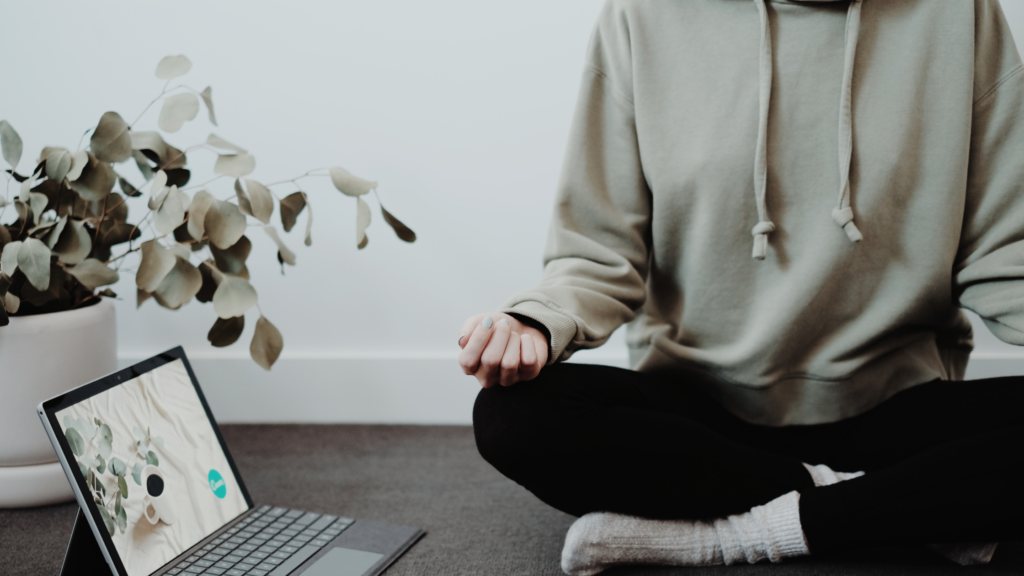 a person meditating by laptop