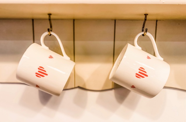 2 fine bone china mugs with hearts design hanging on a kitchen dresser