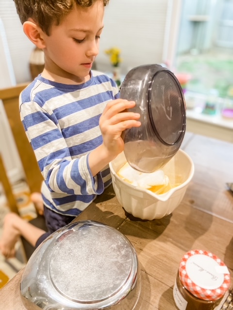 Boy adding sugar to butter in a mixing bowl