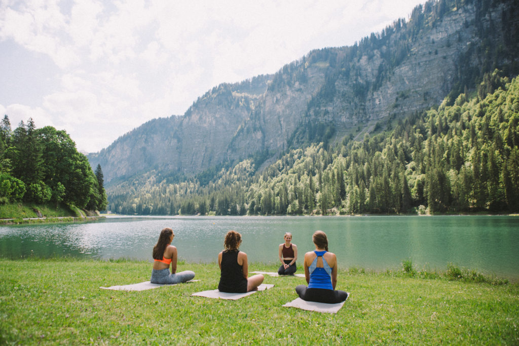 Ladies in the French alps sitting cross legged by a leg practicing yoga