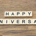 Happy Anniversary written out in scrabble letters on a wooden table