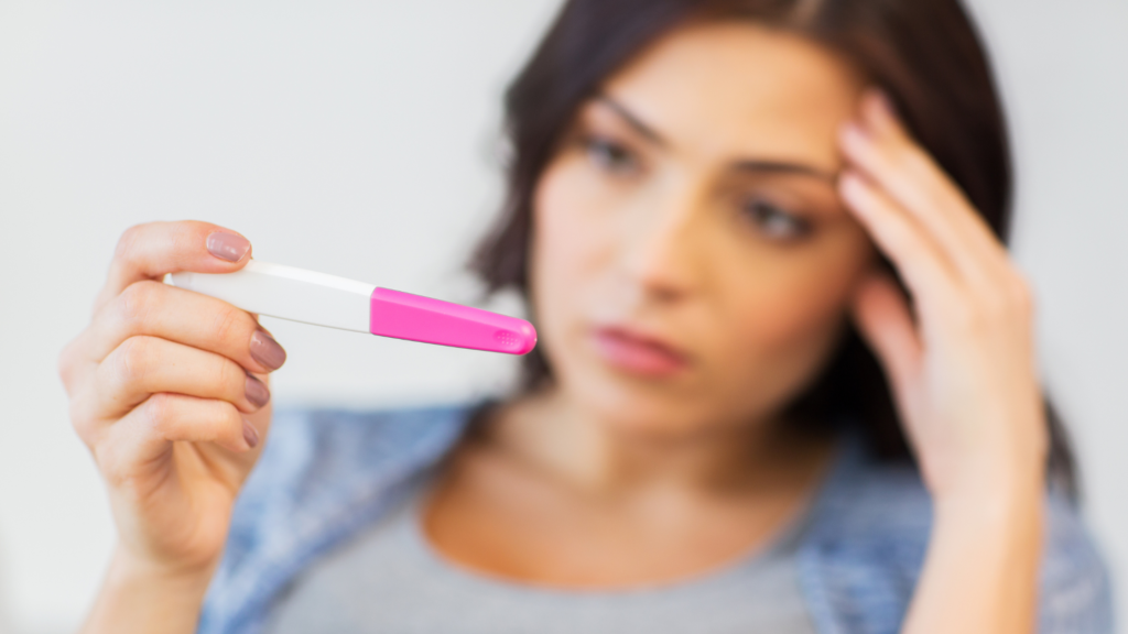 Woman looking sad looking at a pregnancy test