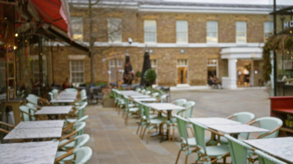 Blurred photo of street cafe scene in London with tables and chairs set up for outside dining