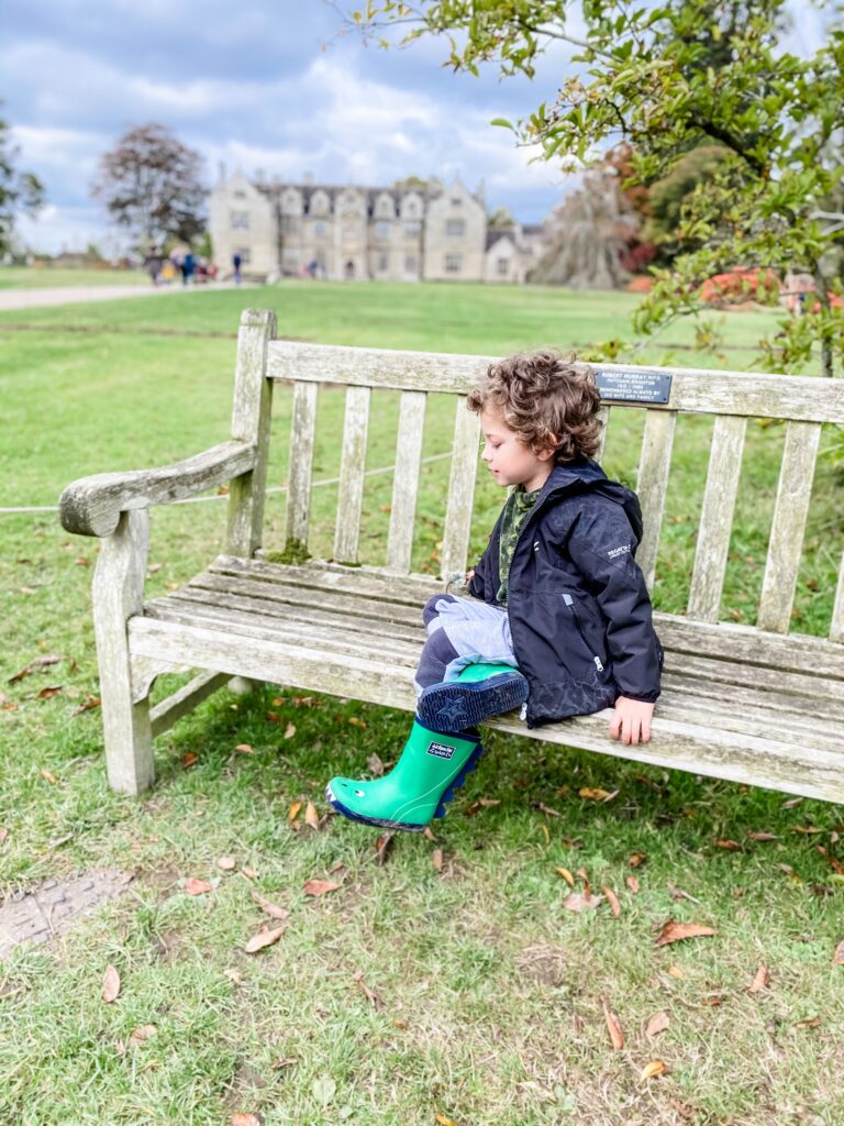Youn boy on a bench outside the mansion at wakehurst place
