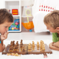 Two seven year olds playing chess together on the floor