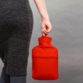 The back of a woman outside holding a red hot water bottle