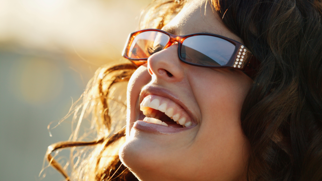 Lady laughing on a sunny day wearing tortoiseshell Sunglasses