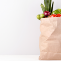 Groceries in a brown paper bag with white background