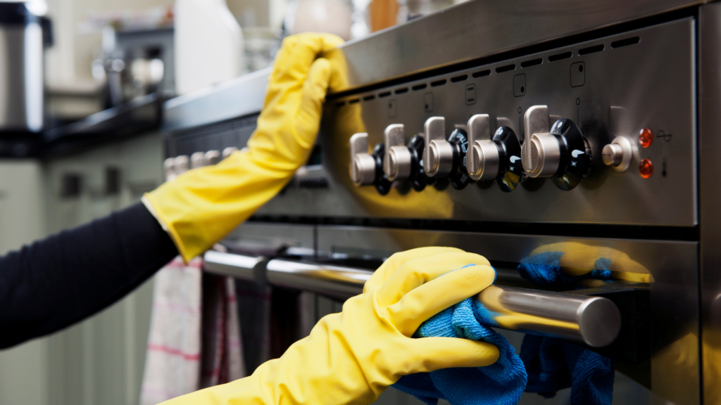 Hands in yellow marigolds cleaning the oven
