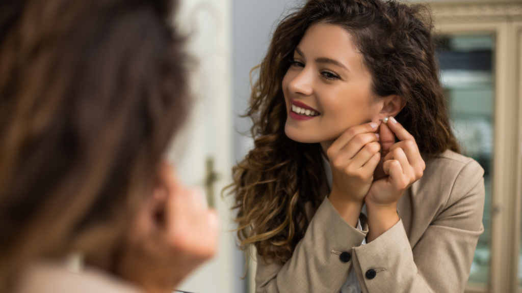A woman putting on her earrings to finish off her autumn outfit
