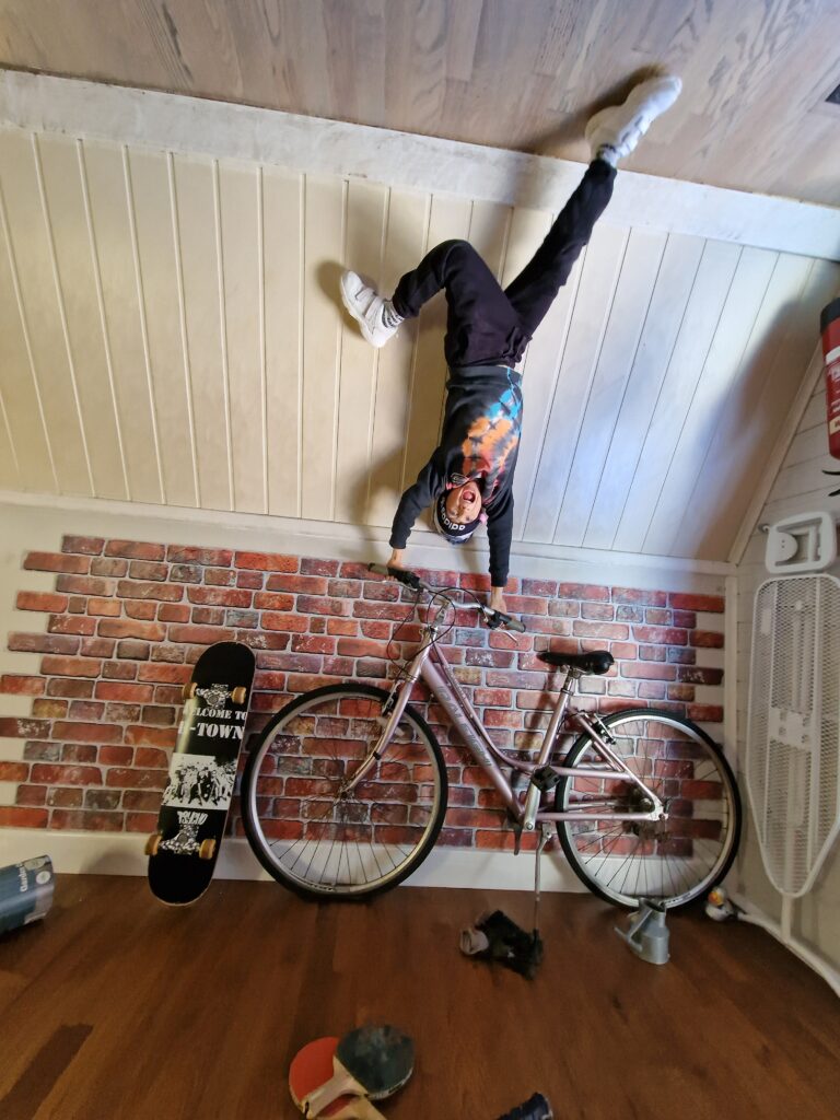 Boy at the Upside Down House in Brighton holding on to a bike