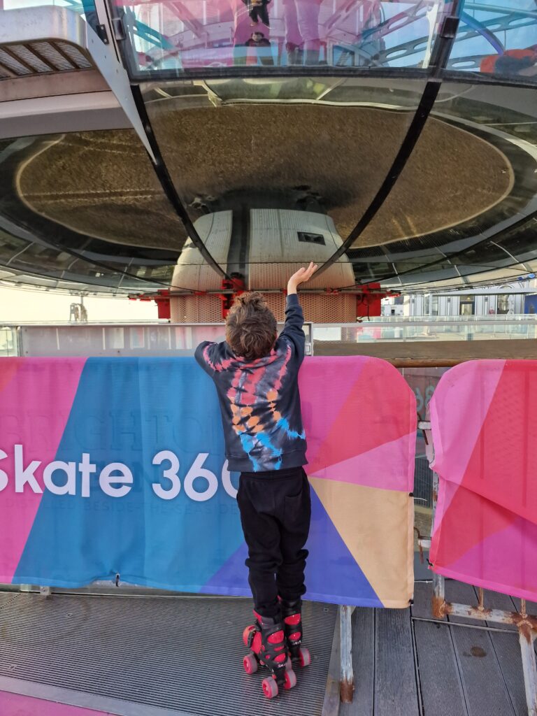 Boy waving at people in the i360 pod at 360 Skate in Brighton