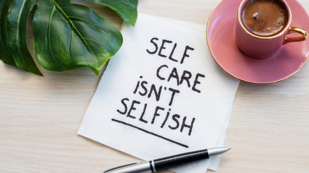 Seld Care Isn't Selfish written in black ink on a napkin next to a coffee and a leaf