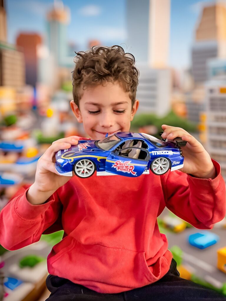 Boy with street fighter collectible with toy town landscape behing him