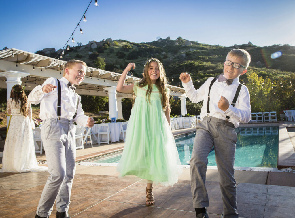 Happy kids dancing at a wedding outdoors by the pool