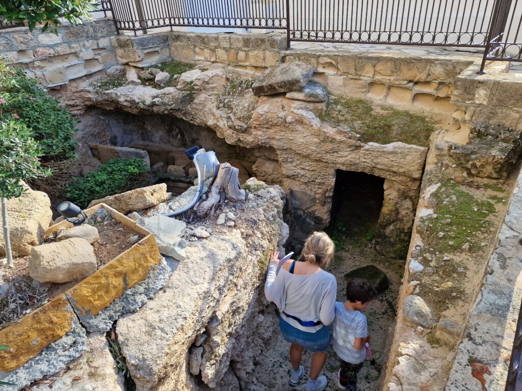 Mum and son climbing down into the ancient tombs on the grounds of Alexander the Great beach hotel