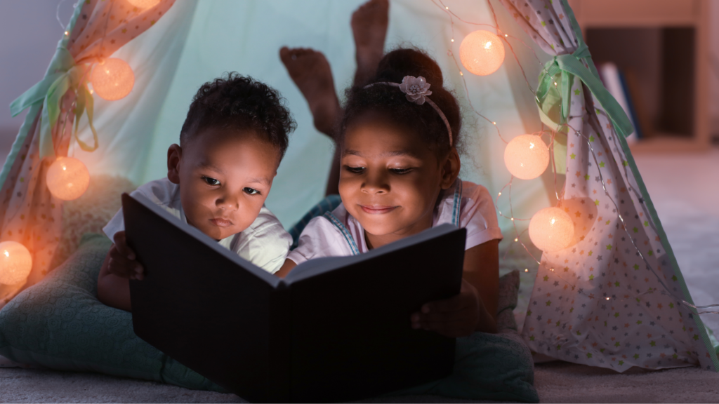Two children in a den reading a book together.