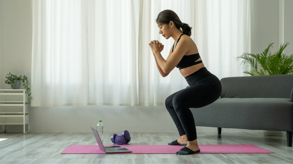 Lady watching her laptop whilst practicing yoga on an online yoga course at home