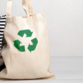 Recycle canvas bag with recycle sign and pile of second hand clothes