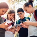 Kids gathered around in a circle looking at their mobile phones