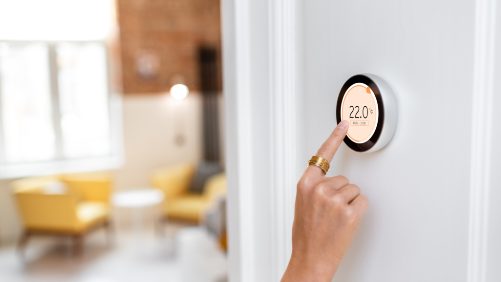 Ladies hand touching a thermostat which is currently set to 22 degrees