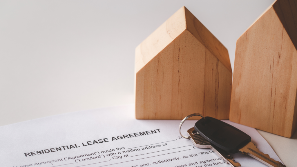 Legal lease agreement with house keys and wooden block houses on desk