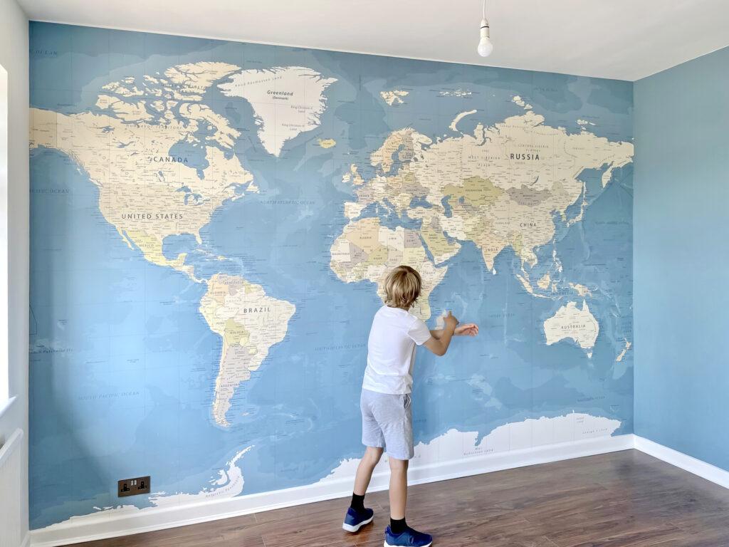 World map wall mural with boy looking at map