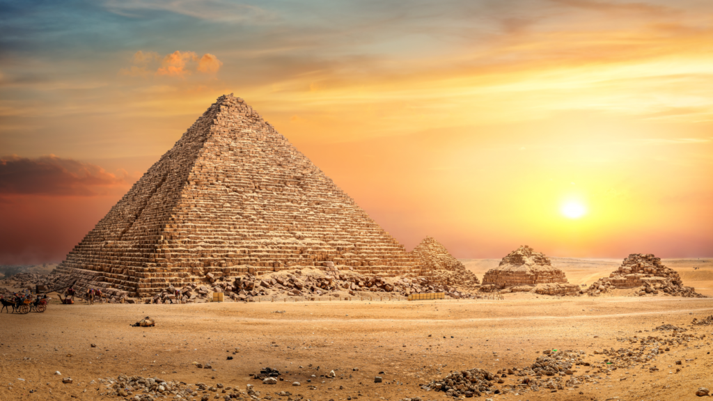 Egyprian pyramid in a sandy desssert with sun starting to set