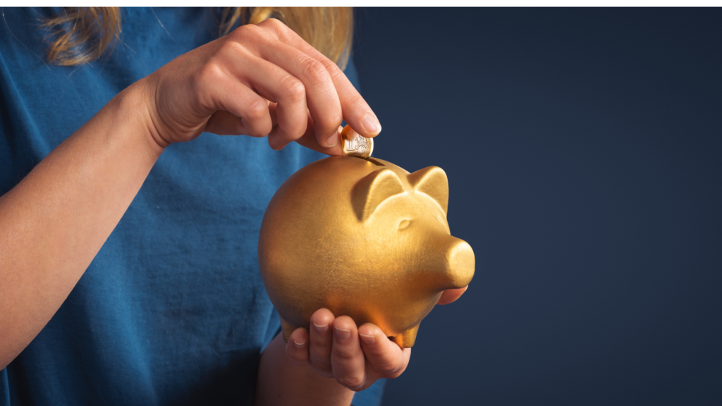 Hand outting a coin into a gold piggy bank