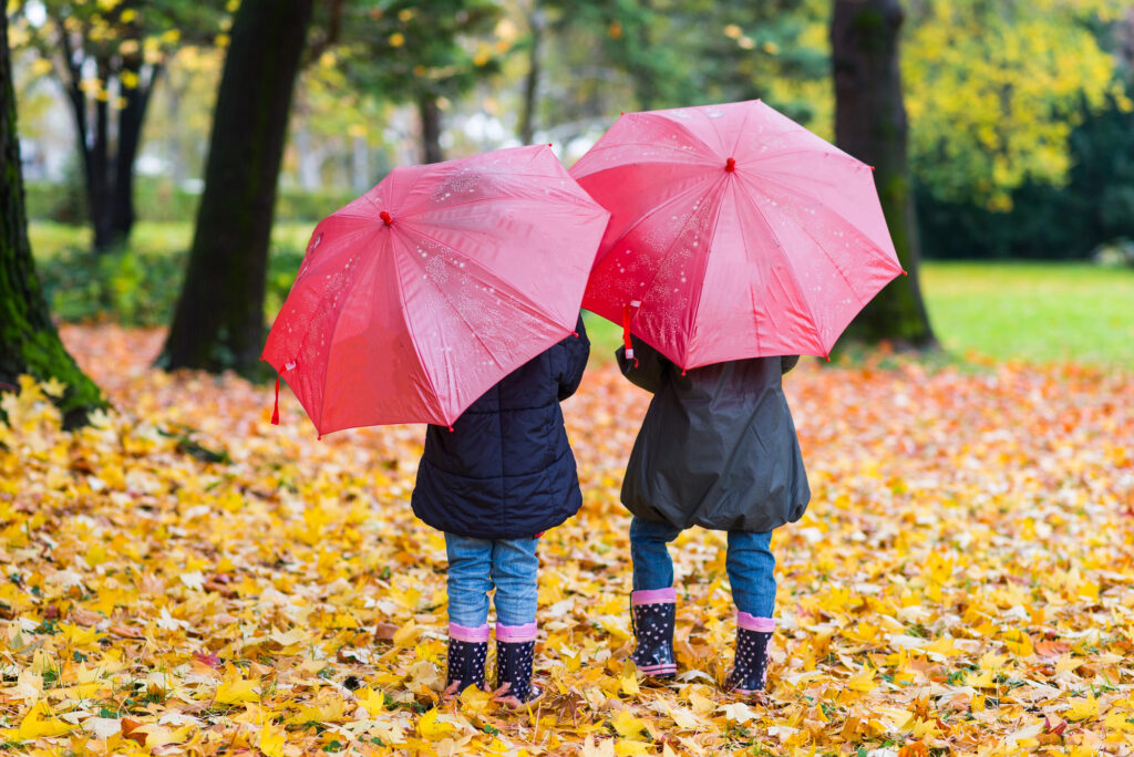 Two girls under pink umbrellas on a rainy day