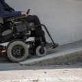 Power chair going up a ramp at building entrance.
