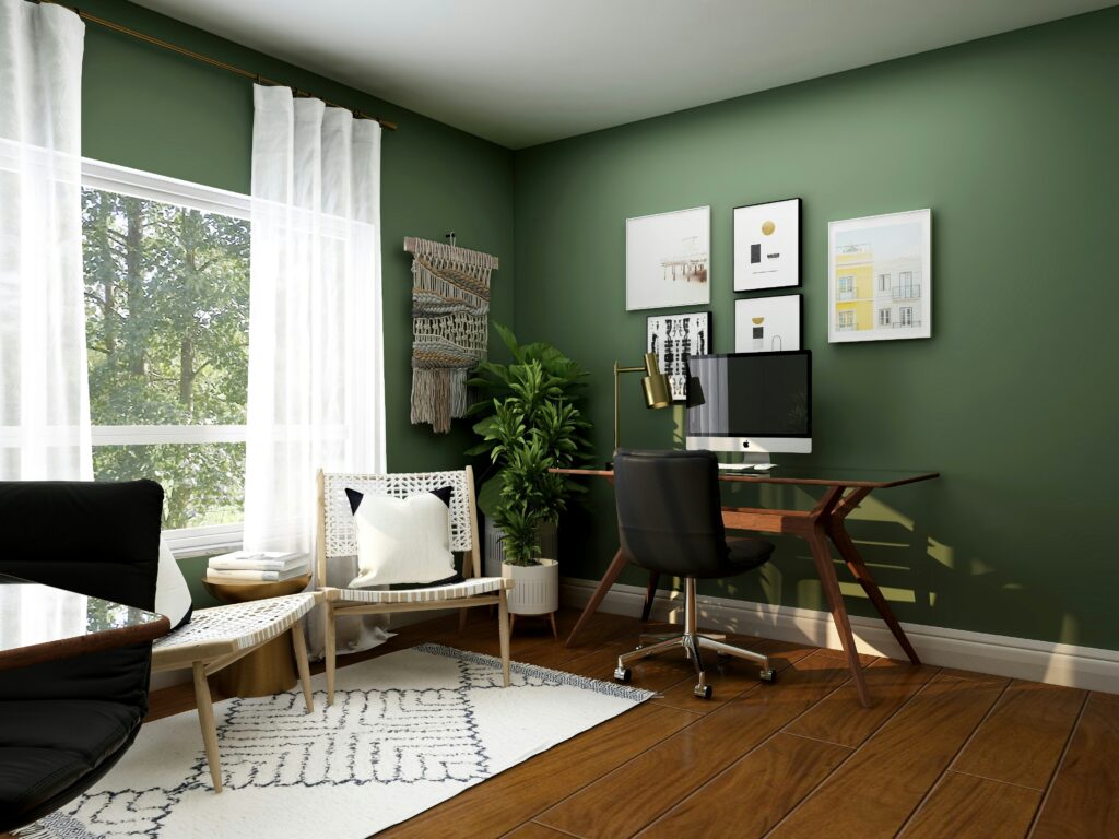 Home office with wooden floors and green walls, desk with a Mac on it and wall art