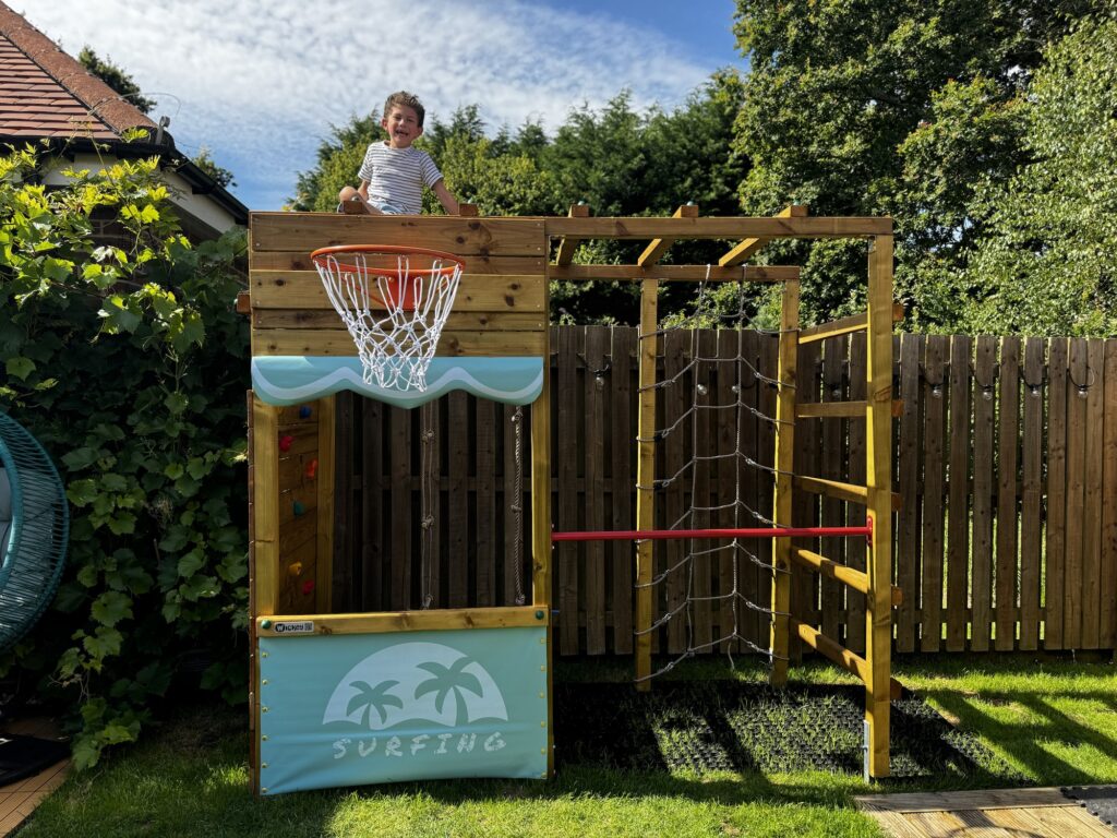 Boy on top oh his Wickey Climbing Tower having lots of fun in his back garden