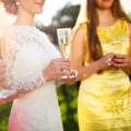 Bride with four happy bridesmaids in bright coloured dresses toasting at a wedding reception