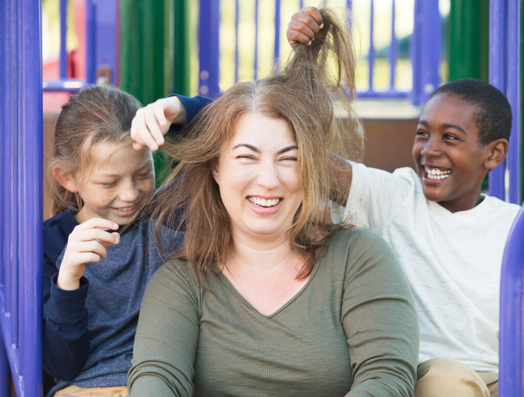 A laughing mother sitting with two foster sons playing with her hair