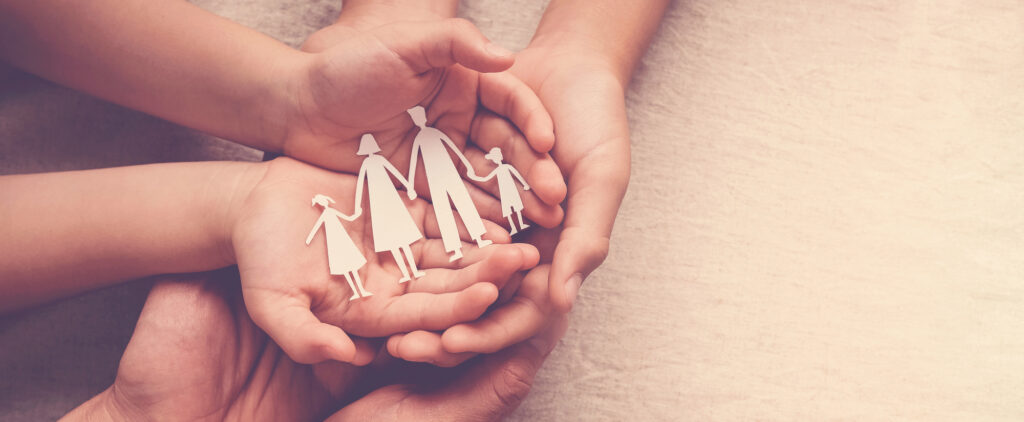 Paper cut out of a family being held in a parents and child's hand to represent foster care