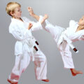 Two kids, a girl and a boy, in karate gee with gurl karate kicking boy and boy blocking