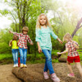 Children playing outside and balancing on a log